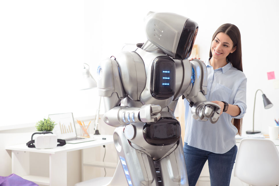 Eine Frau steht neben einem humanoiden Roboter und hält dessen Arm