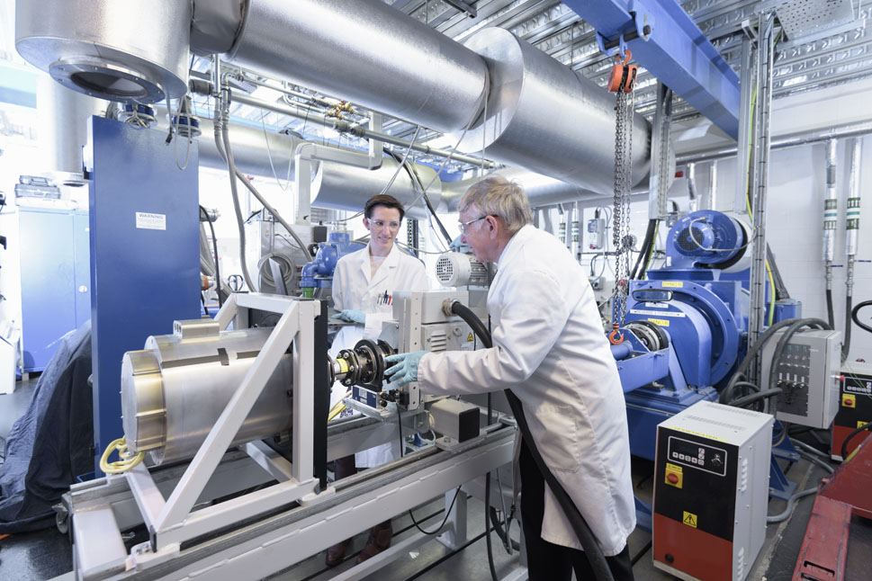 Bild zeigt zwei Wissenschaftler - eine Frau und einen Mann - die an einer Maschine arbeiten