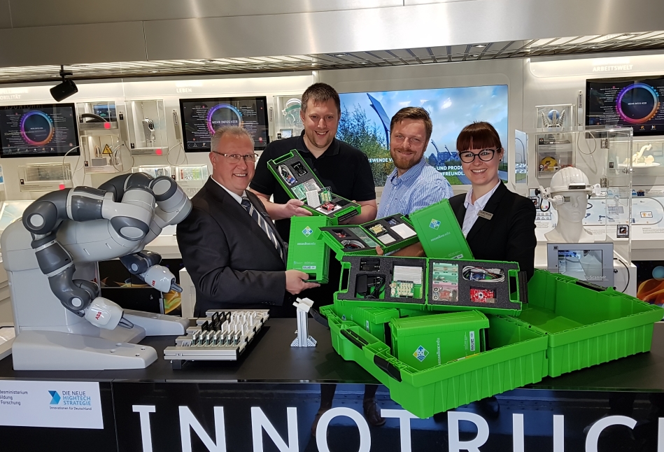 Die InnoTruck-Wissenschaftler Dr. Andreas Jungluth und Eva Zolnhofer vergeben gemeinsam mit Dr. Thomas Bartoschek, Leiter des senseBox-Teams, den ersten Klassensatz an Hendrik Büdding.